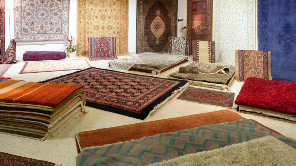 Ekspozycja r贸偶norodnych dywan贸w r臋cznie tkanych, z wzorami etnicznymi i tradycyjnymi, na drewnianej pod艂odze